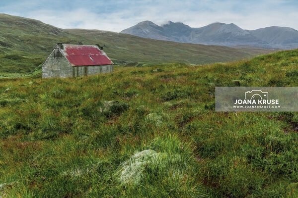 The Fain Bothy, also known as Fainmore House, is a traditional bothy with a bright red roof, nestled amidst the boggy Scottish Highlands.