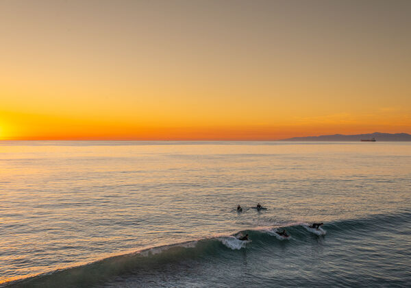 Surfers catch the last wave of the day at Manhattan Beach, California, USA. Taken from the pier.