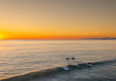 Surfers catch the last wave of the day at Manhattan Beach, California, USA. Taken from the pier.